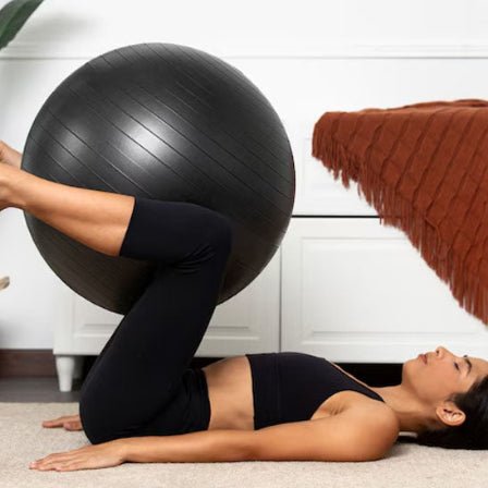 Ballon pilates noir avec femme en position de pilates