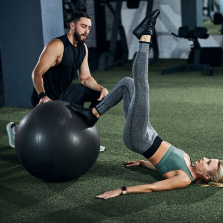 Ballon pilates noir et couple qui fait des exercices exterieur