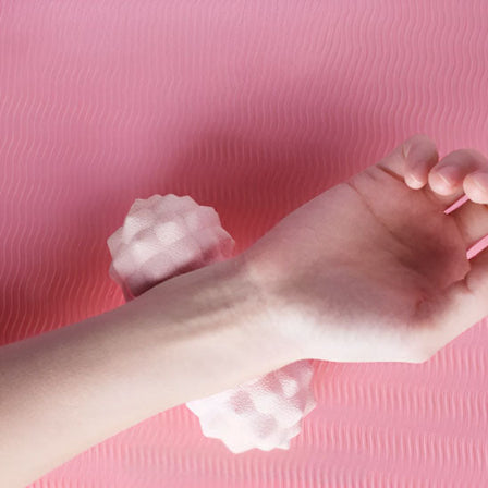 boule de massage couleur rose et une femme qui messe sn poignet