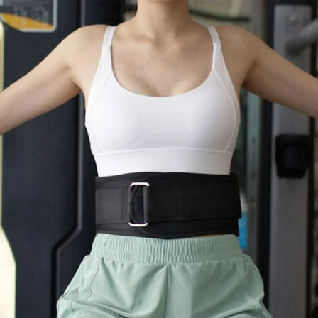 Femme portant une ceinture de force dans une salle de sport, concentrée sur son entraßnement.
