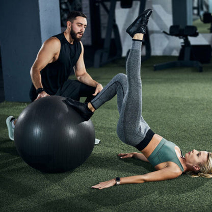 Ballon pilates noir et couple qui fait des exercices exterieur