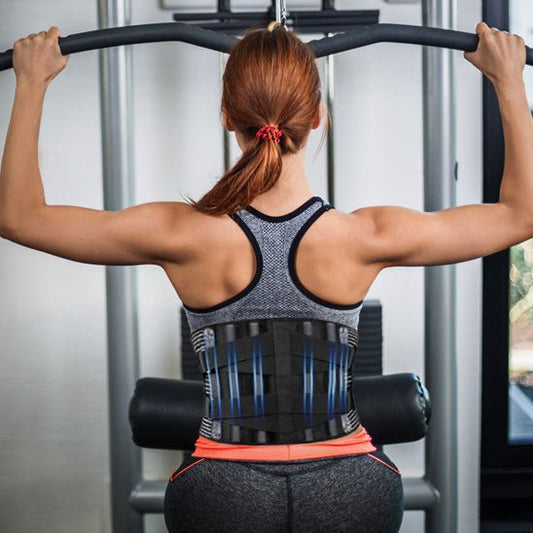 Une femme portant une ceinture lombaire s'exerce dans une salle de sport.