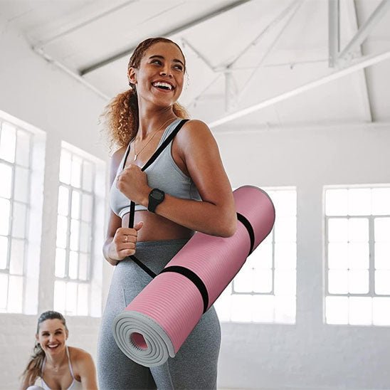 Femme avec le tapis de gym Confort Pro 10mm rose dans une salle de yoga